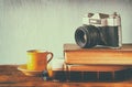 Stack of books, old clock and vintage camera over wooden table. image is processed with retro faded style Royalty Free Stock Photo