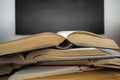 Stack of books with open book on wooden desk against blackboard background Royalty Free Stock Photo