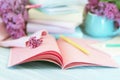 Stack of books, open notepad, pencils, cup of tea and fresh lilac flowers on wooden table, back to school concept Royalty Free Stock Photo