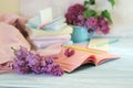 Stack of books, open notepad, pencils, cup of tea and fresh lilac flowers on wooden table, back to school concept Royalty Free Stock Photo