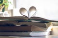 Stack of books with open one at the top. Heart of pages on background of open window. Love to read concept Royalty Free Stock Photo