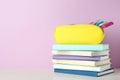 Stack of books and pen case on table against color background Royalty Free Stock Photo