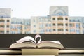 Stack of books, pen oin the window with city view with top one opened and pages forming heart shape. Royalty Free Stock Photo