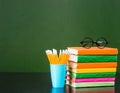 Stack of books and pencils near empty green chalkboard Royalty Free Stock Photo