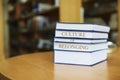 Stack of books with phrase Culture of Belonging on table in library. Space for text