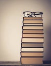Stack of Books with Reading Glasses on Wood Table Against Neutral Background Royalty Free Stock Photo