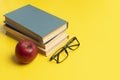 stack of books, red apple and glasses isolated on colorful surface, simple abstract study concept Royalty Free Stock Photo