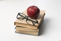 stack of books, red apple and glasses isolated on colorful surface, simple abstract study concept Royalty Free Stock Photo