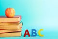 A stack of books with a red apple and letters of the ABC English alphabet stand on a blue background. The concept of education and Royalty Free Stock Photo