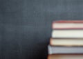 Stack of books resting in front of a chalkboard