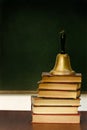 Stack of books and school bell on desk Royalty Free Stock Photo