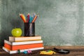 A Stack of books and stationery and an apple on the background of the school board. Royalty Free Stock Photo