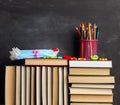 Stack of books, stationery and disposable medical face masks on black chalk board background Royalty Free Stock Photo