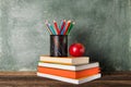 A Stack of books and stationery and a red apple on the background of the school board. Royalty Free Stock Photo