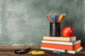 a Stack of books and stationery and a red apple on the background of the school board. Royalty Free Stock Photo