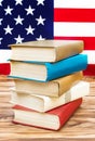 Stack of books on the table against american flag. American education Royalty Free Stock Photo