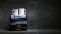 Stack of books with various subjects and two cups of coffee