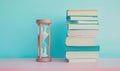 Stack of books on a white table with a pastel periwinkle background, with an hourglass Royalty Free Stock Photo