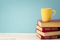 Stack of books and yellow mug against blue background. Copy spac Royalty Free Stock Photo