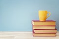 Stack of books and yellow mug against blue background. Copy spac Royalty Free Stock Photo