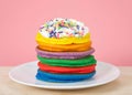 Stack of bright colorful pancakes topped with whipped cream and candy sprinkles