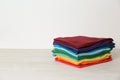 Stack of bright folded clothes on table against white background Royalty Free Stock Photo