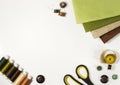 Stack of brown and green fabrics surrounded by sewing and quilting accessories on white background