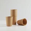 A stack of brown paper cups and one separate cup are arranged on a white surface. T Royalty Free Stock Photo