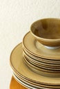 Stack of brown speckled glazed earthenware ceramic plates dishes and bowls on wooden table. White wall background Royalty Free Stock Photo