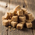 A stack of brown sugar cubes lies on a rustic wooden surface. The cubes are irregula Royalty Free Stock Photo