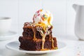 Stack of brownie squares with scoop of ice cream, caramel and sprinkles, white background Royalty Free Stock Photo
