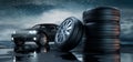 Stack of car wheels and tires with black car in the rain Royalty Free Stock Photo