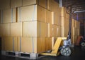 Stack of Card Board Boxes with Hand Pallet Truck. Interior of Storage Warehouse. Cargo Shipment Export- Import. Royalty Free Stock Photo