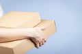 Stack of cardboard boxes in female hands. Blank brown parcel boxes on light blue background. Packaging, shopping, free Royalty Free Stock Photo