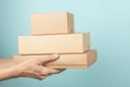 Stack of cardboard boxes in female hands. Blank brown parcel boxes on light blue background. Mock up. Packaging Royalty Free Stock Photo