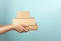 Stack of cardboard boxes in female hands. Blank brown parcel boxes on light blue background. Mock up. Packaging Royalty Free Stock Photo