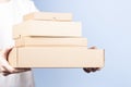 Stack of cardboard boxes in female hands. Blank brown parcel boxes on light blue background. Packaging, shopping, free Royalty Free Stock Photo