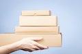 Stack of cardboard boxes in female hands. Blank brown parcel boxes on light blue background. Packaging, shopping, free Royalty Free Stock Photo