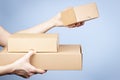 Stack of cardboard boxes in female hands. Blank parcel boxes on light blue background. Packaging, shopping, free