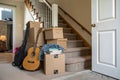 Stack of cardboard boxes with guitar and books near staircase Royalty Free Stock Photo