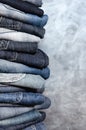 A stack of carelessly folded jeans on gray background. Close-up of jeans in different colors. Copy space Royalty Free Stock Photo