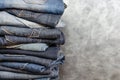 A stack of carelessly folded jeans on gray background. Close-up of jeans in different colors. Copy space