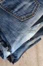 A stack of carelessly folded jeans on wooden background. Close-up of jeans in different colors. Copy space Royalty Free Stock Photo