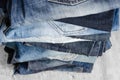 A stack of carelessly folded woman`s jeans on gray background. Close-up of jeans in different colors. Selective focus Royalty Free Stock Photo