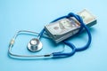 Stack of cash dollars and stethoscope on blue background. The concept of medical strechevka or expensive medicine, doctors salary Royalty Free Stock Photo