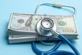 Stack of cash dollars and stethoscope on blue background. The concept of medical strechevka or expensive medicine Royalty Free Stock Photo