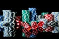 Stack of Casino gambling chips and red dices isolated on reflective black background Royalty Free Stock Photo