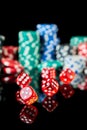 Stack of Casino gambling chips and red dices isolated on reflective black background Royalty Free Stock Photo