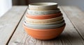 A stack of ceramic bowls is arranged on a rustic wooden table. The bowls feature earthy tones, Royalty Free Stock Photo