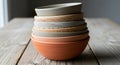 A stack of ceramic bowls rests on a wooden table. Each bowl varies slightly in size and color, with Royalty Free Stock Photo